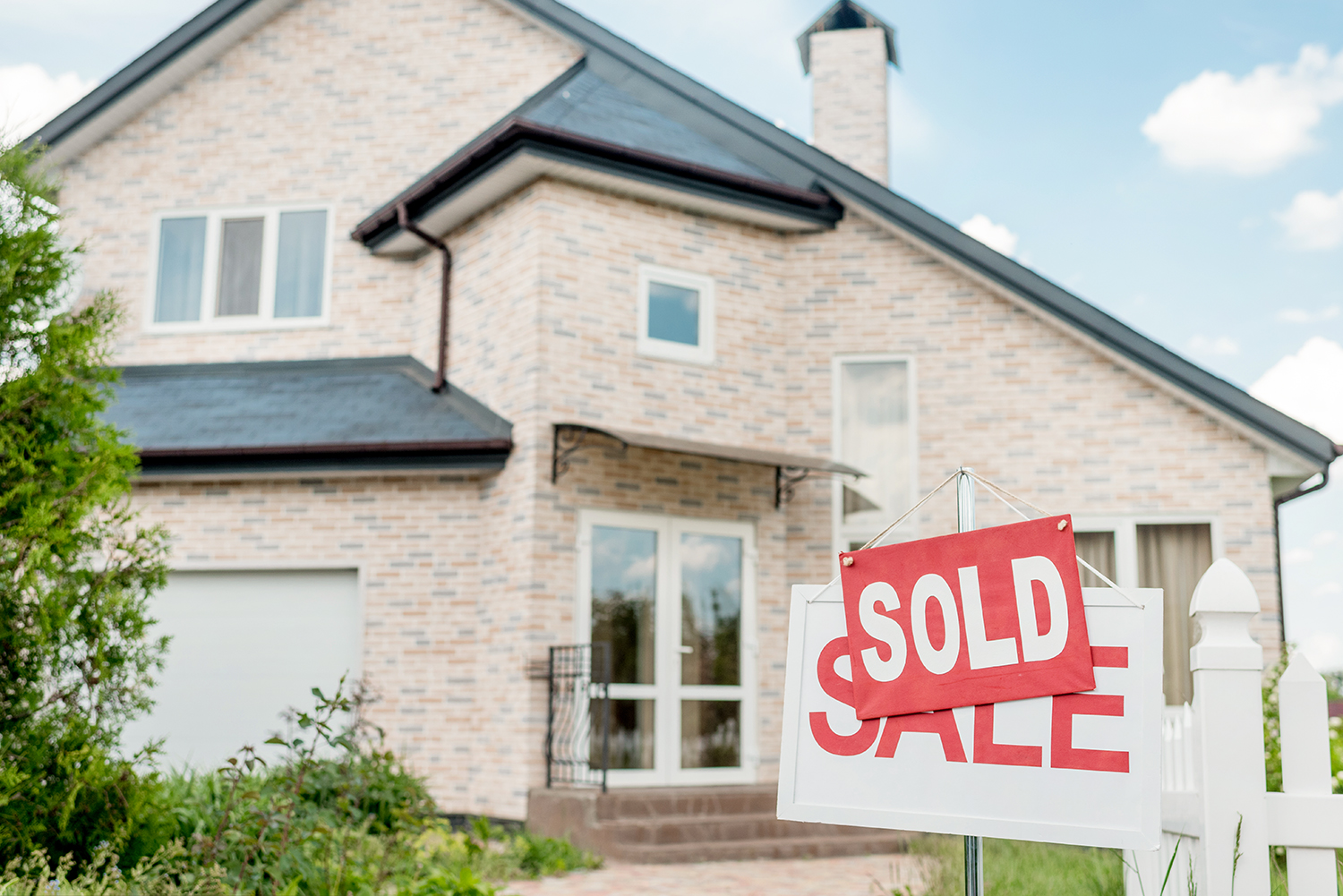 A charming two-story brick house in East Tennessee proudly displays a "Sold" sign, testament to expert property management. The home features a welcoming front porch and numerous windows, all basking under a clear blue sky.